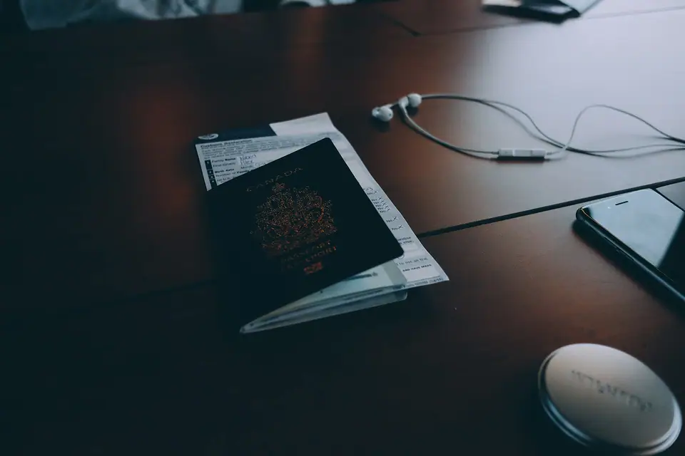 Karanlık bir masanın üzerinde kapalı bir pasaport, kulaklık ve telefon